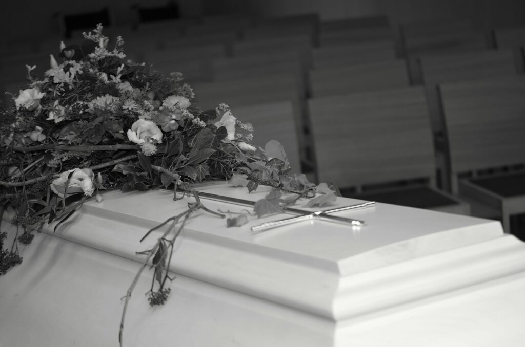 A white casket adorned with flowers inside a serene chapel, evoking calm and reflection.