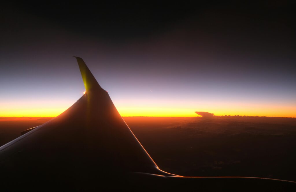 A breathtaking view from an airplane window showcasing a colorful sunset over the horizon.