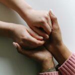 Close-up of diverse hands holding, symbolizing care, support, and friendship.