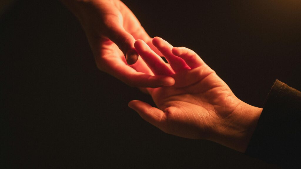 Close-up of two hands reaching towards each other, creating an intimate connection.
